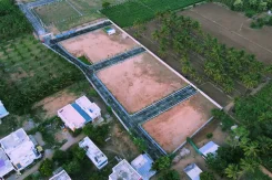 Exclusive Gated Community Open Land Plots in Coimbatore A serene garden with wooden benches and a white picket fence under a clear blue sky.
